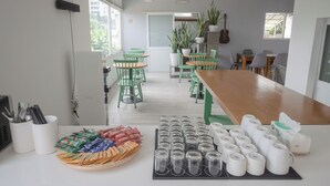 A modern dining area with green chairs, a wooden table, and a variety of food items and supplies on the counter. - COMMON INN Thao Dien (Ho Chi Minh City)