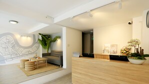 A modern reception area with a wooden reception desk, a large potted plant, and a map mural on the wall. - COMMON INN Thao Dien (Ho Chi Minh City)