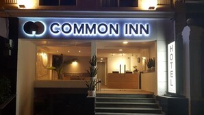 The exterior of the Common Inn hotel with a well-lit entrance, a reception desk, and a staircase leading to the lobby. - COMMON INN Thao Dien (Ho Chi Minh City)