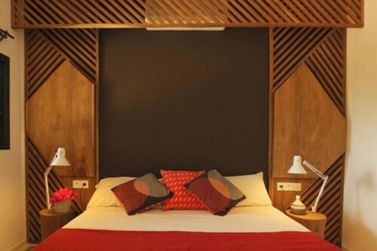 A bedroom with a large bed, two bedside tables with lamps, and a wooden headboard with a geometric pattern.