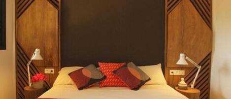 A bedroom with a large bed, two bedside tables with lamps, and a wooden headboard with a geometric pattern.