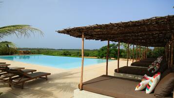 Alberca al aire libre, sombrillas en la alberca y camastros