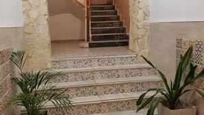 Una escalera con baldosas decoradas, flanqueada por muros de piedra y macetas con plantas.
