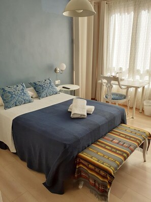 A bedroom with a bed, bedside table, lamp, chair, and a bench.