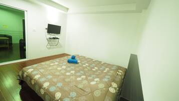 A bedroom with a bed, a TV mounted on the wall, and a sliding door leading to another room.