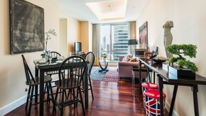 A modern living room with a dining area, a sofa, a TV, and a large window with a city view.