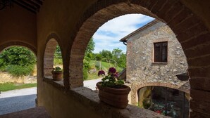 A stone building with arched windows and a potted plant on the ledge. - Agriturismo Cerreto (Pienza)