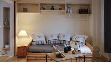 Una habitación acogedora con una cama de madera, una mesita de noche, una lámpara y estanterías con libros y objetos decorativos.