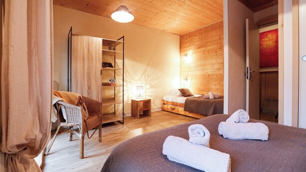 A cozy room with a bed, a chair, a small table, and a bookshelf. - Auberge Les 2 Moucherolles (Correncon-en-Vercors)