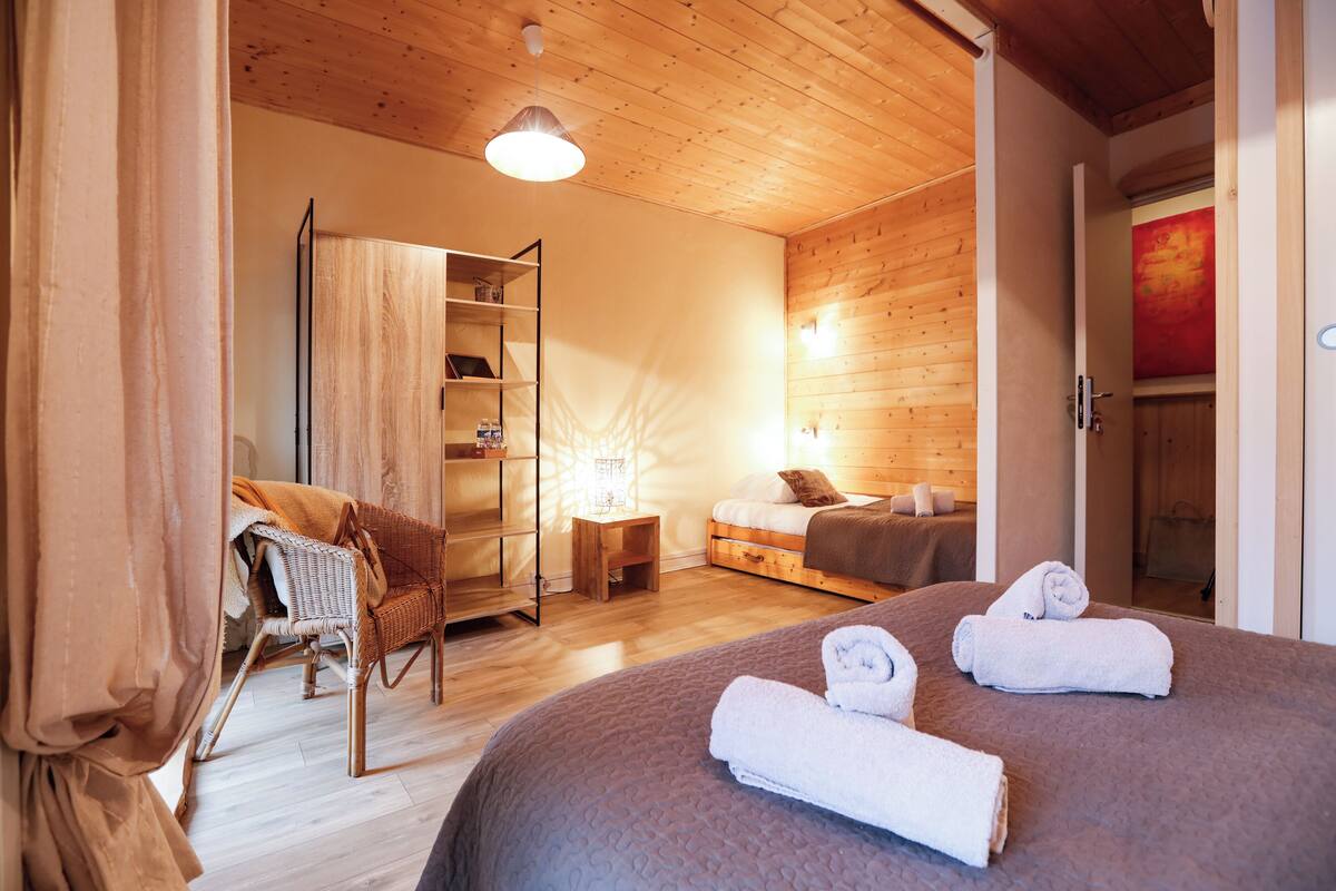 Une pièce confortable avec un lit, une chaise, une petite table et une bibliothèque.