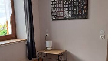 A bedroom with a bed, towels, a lamp, and a wall art of buildings.