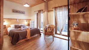 A cozy bedroom with a wooden bed, a wicker chair, and a shelf with books. - Auberge Les 2 Moucherolles (Correncon-en-Vercors)