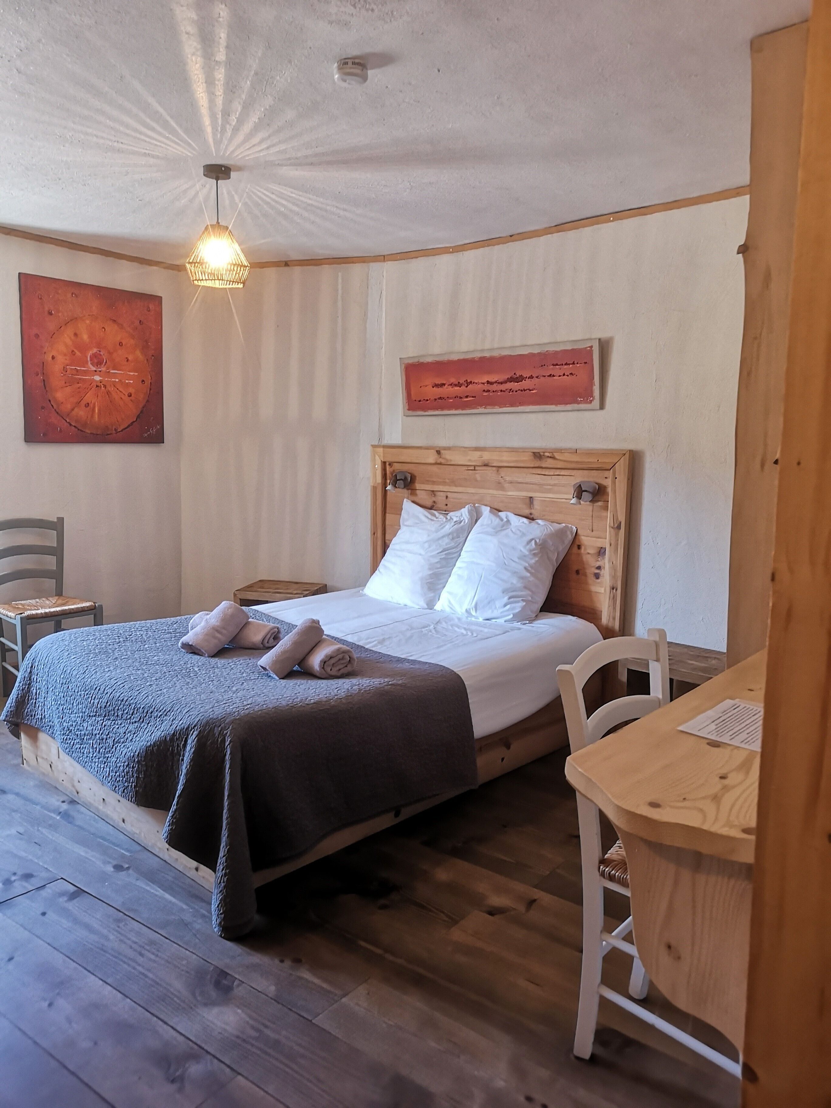 A neatly arranged bedroom with a wooden bed, a small desk, and a chair.