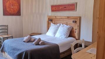 A neatly arranged bedroom with a wooden bed, a small desk, and a chair.