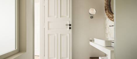 A bathroom with a white door, a marble-tiled floor, a white sink, and a towel rack.
