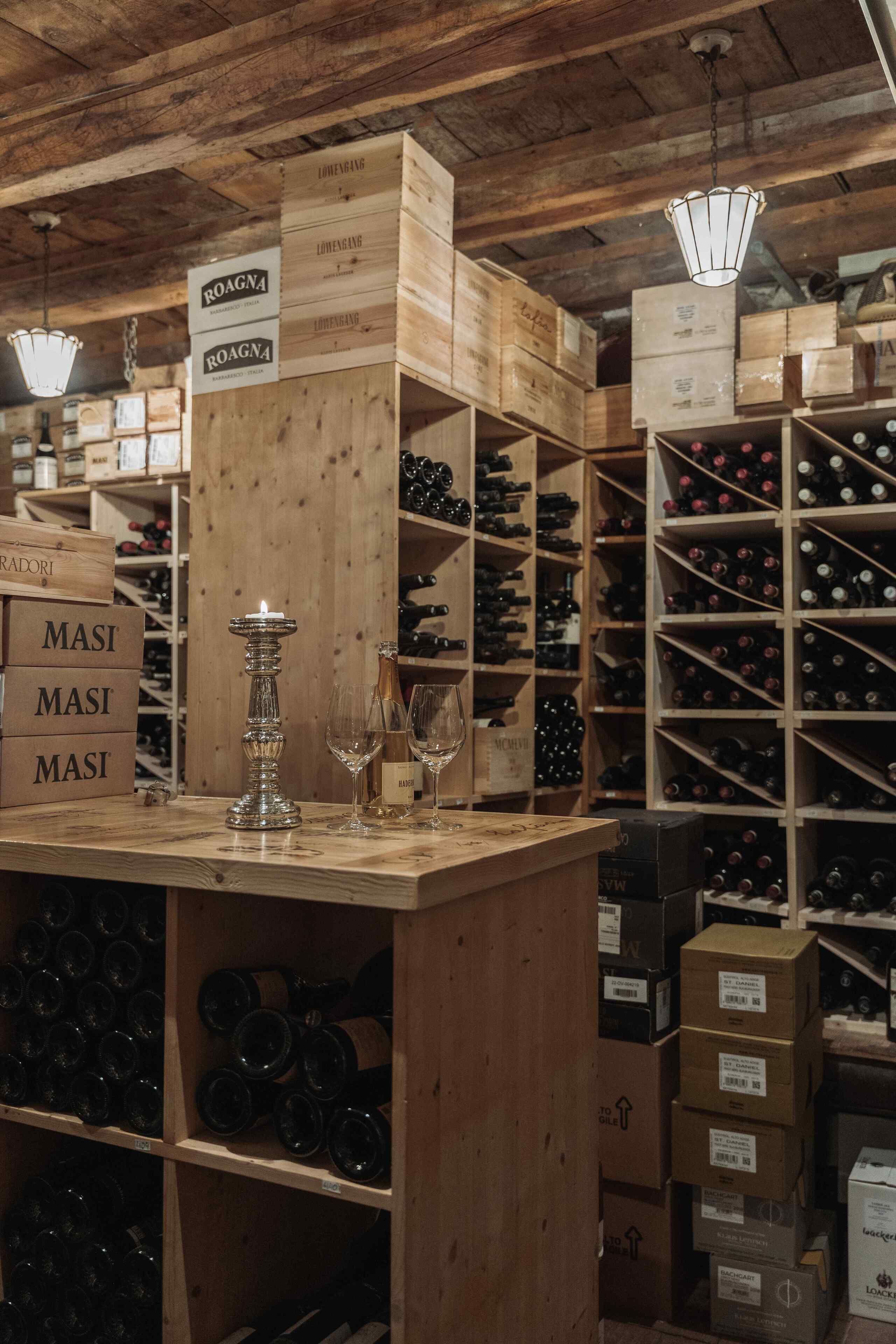 A wine cellar with wooden shelves and boxes labeled with names like "ROAGNA" and "MASI".