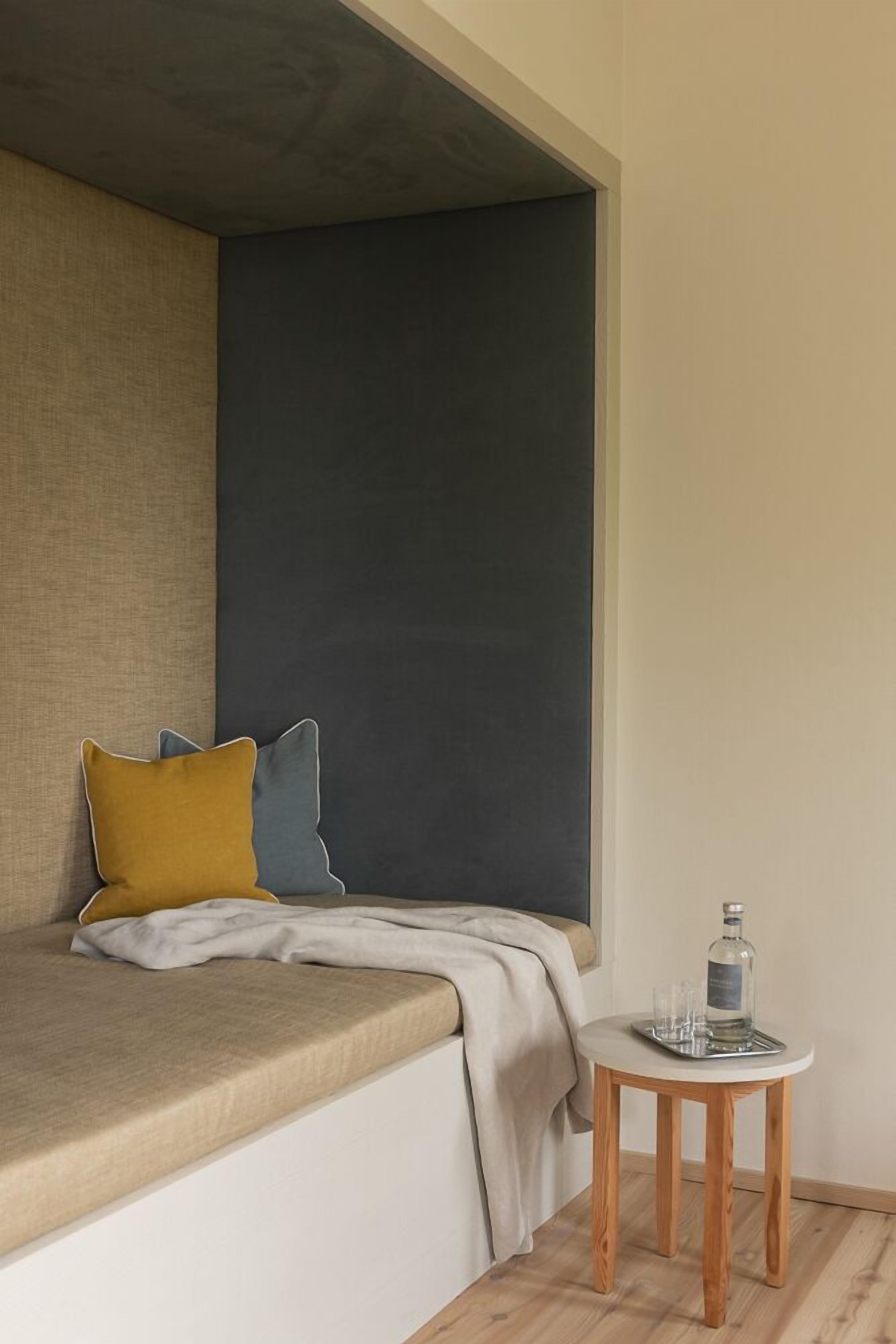 A modern room with a bed, a small table with a bottle and glasses, and a large window.
