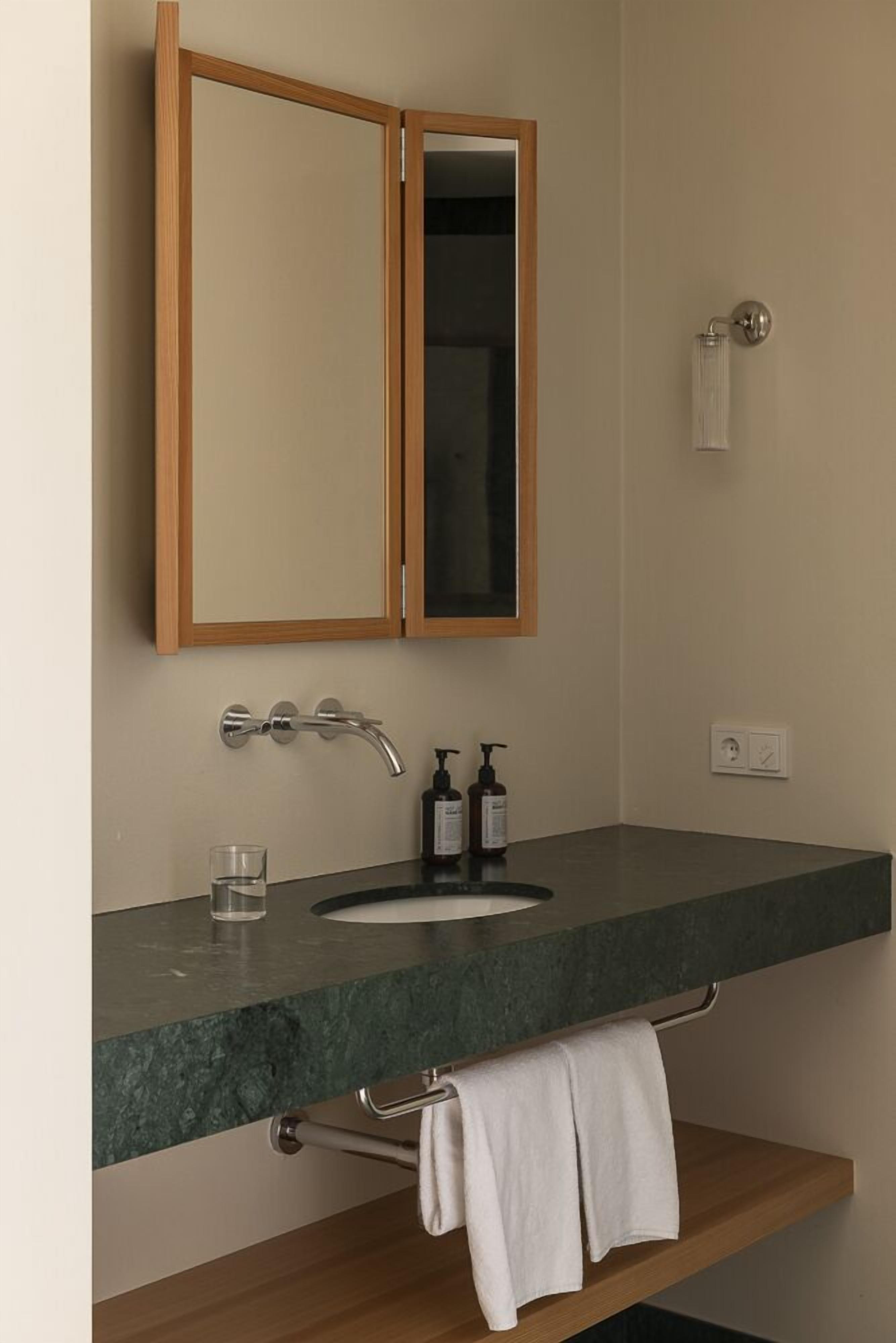 A bathroom with a wooden cabinet, a mirror, a sink with a faucet, and a towel rack.