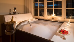 A bathtub filled with bubbles, a champagne bottle, and a bowl of strawberries. - Gasthof Kohlern (Bolzano)