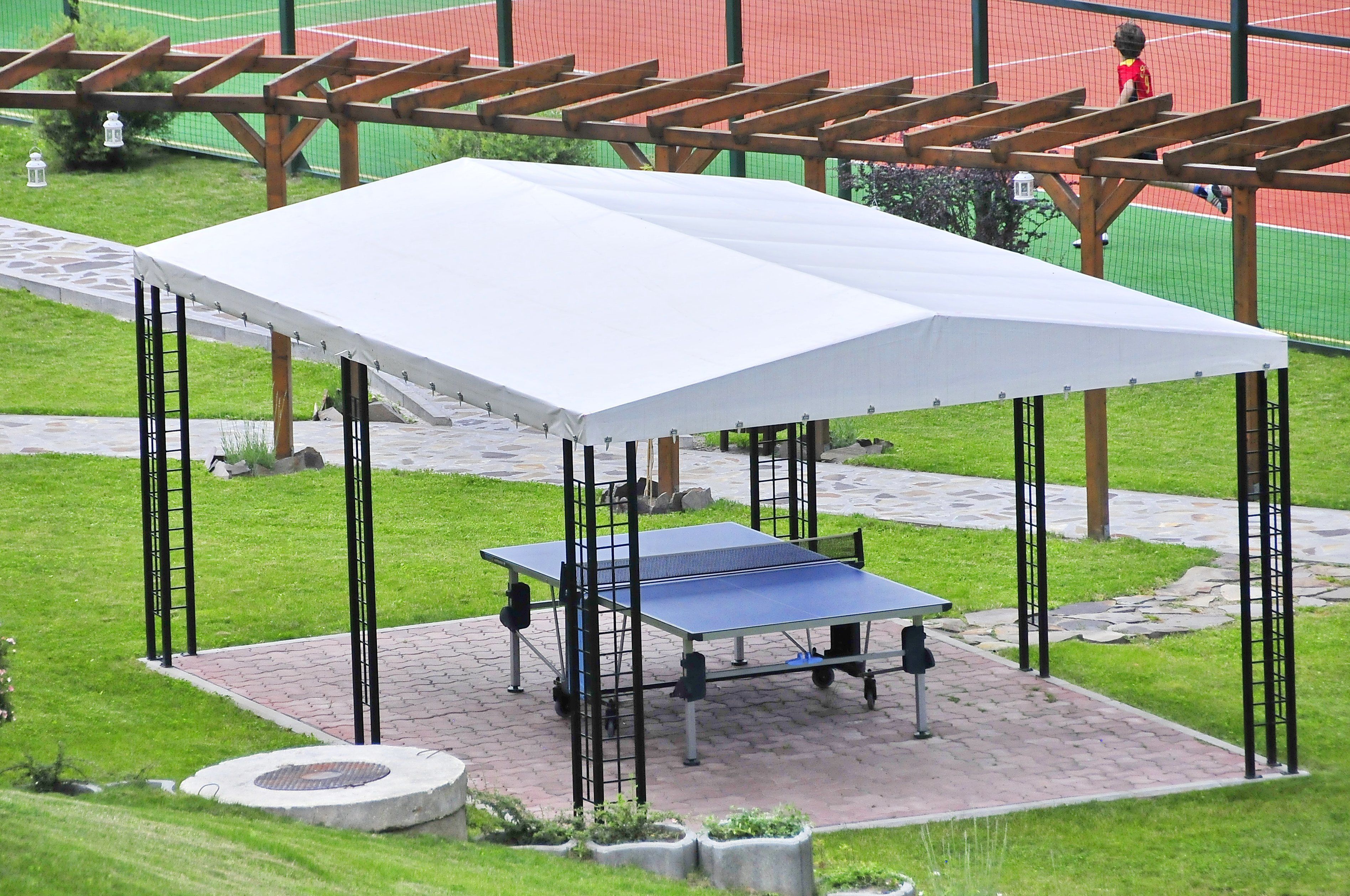 A ping pong table under a white canopy in an outdoor setting.