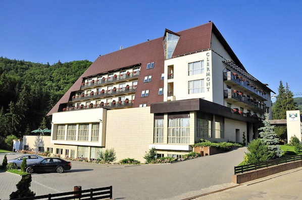 A multi-story hotel with a modern design, featuring balconies with flower boxes and a prominent entrance.