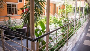 A corridor with a metal railing, potted plants, and a checkered floor. - Primal Hotel (Lagos)