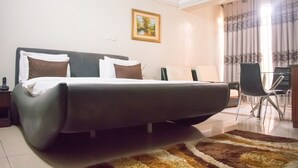 A hotel room with a large bed, a desk, a chair, and a painting on the wall. - Primal Hotel (Lagos)