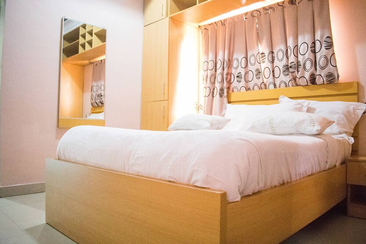 A neatly made bed with white linens, a wooden headboard, and a bedside table.