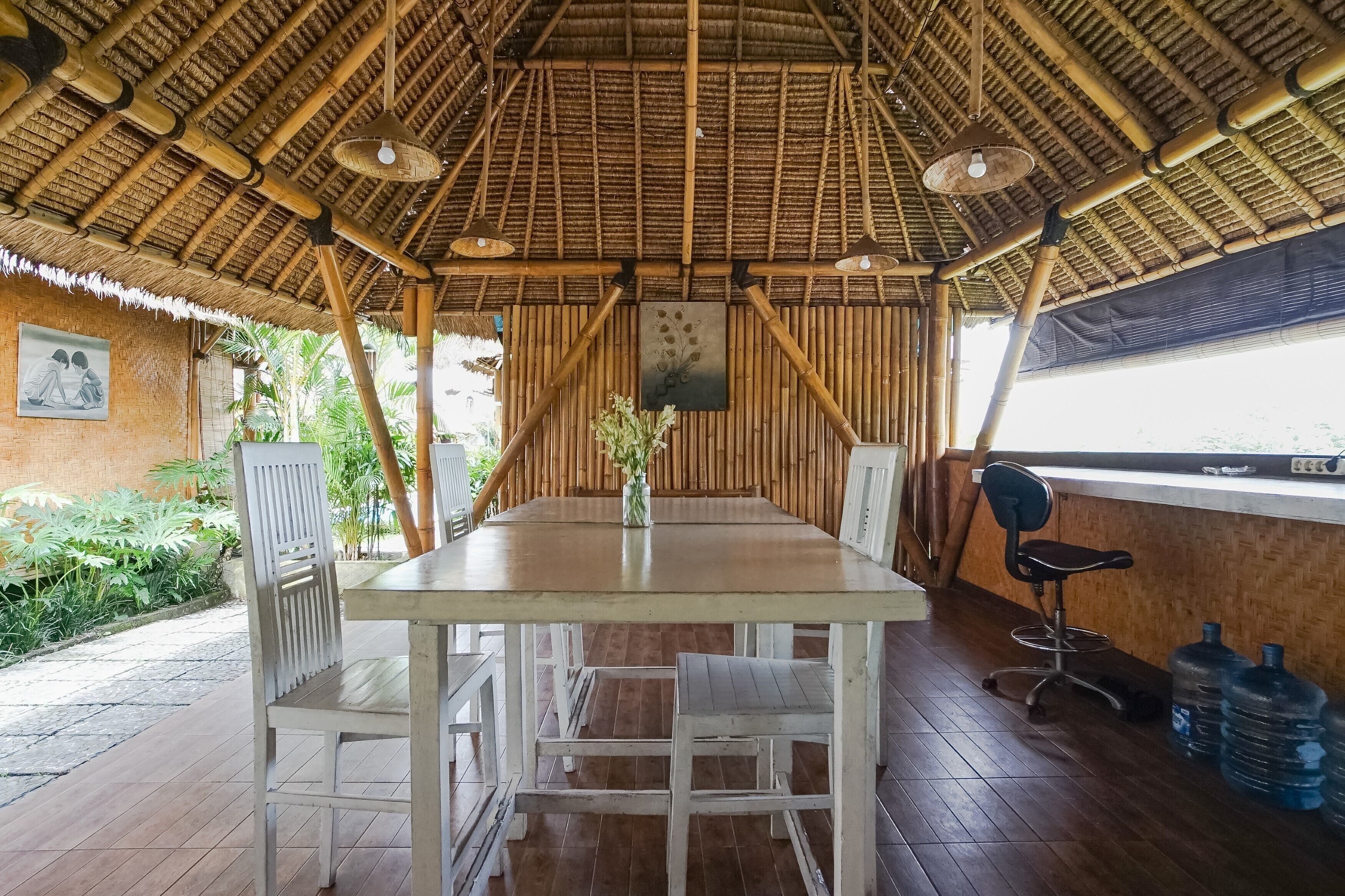 Un área de comedor con techo de bambú, una mesa, sillas y un ventanal grande.