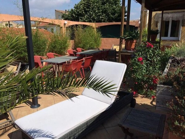 An outdoor seating area with a lounge chair, red chairs, and a table.