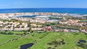 A coastal cityscape with a marina, residential buildings, and a golf course. - Le Gambetta (Vias)