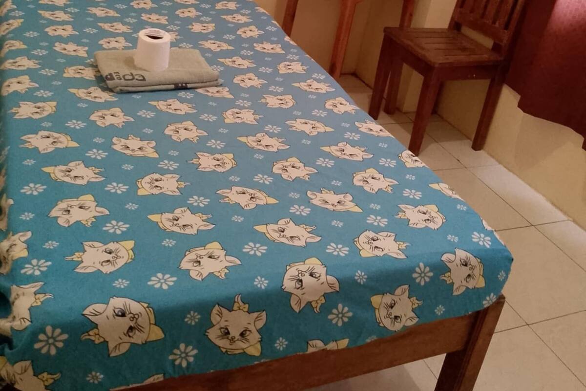 Una habitación pequeña y sencilla con una cama, una mesita y una silla.