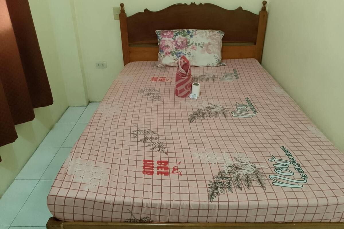 Una cama con un almohadón floral y un edredón estampado con diseño de cuadrícula.