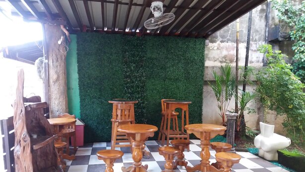 Een terras met houten meubilair en een groene wand.