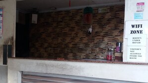 Een receptiegedeelte met een gesloten luik, een prullenbak en een bord dat een WiFi-zone en een kamer in reparatie aangeeft.