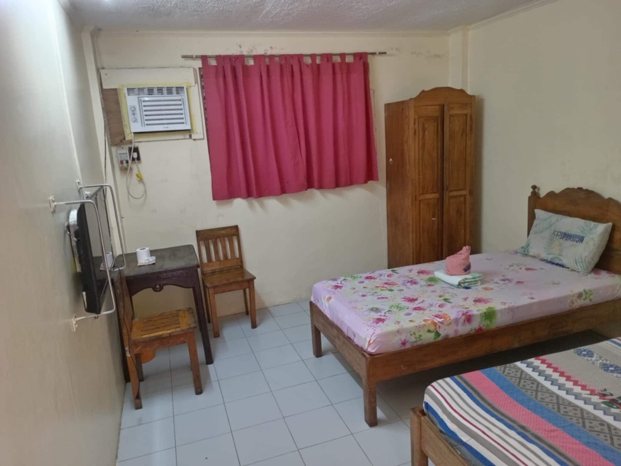 A small, tidy room with a bed, a desk, a chair, and a wardrobe.