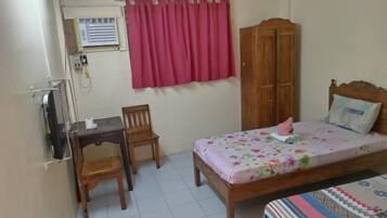 A small, tidy room with a bed, a desk, a chair, and a wardrobe.