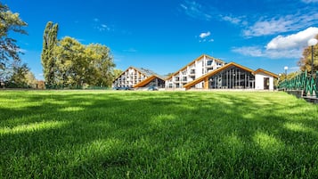 Un edificio moderno con tetto piatto e ampie finestre, circondato da un'area verde curata e alberi.