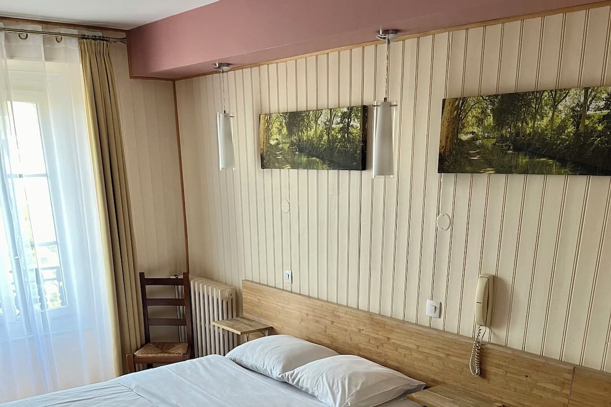Habitación de hotel con dos camas, cabecero de madera, radiador, una mesita y teléfono.