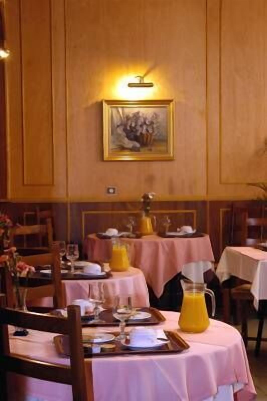 Een eetruimte met gedekte tafels voor het ontbijt, met roze tafelkleden en een kan sinaasappelsap.