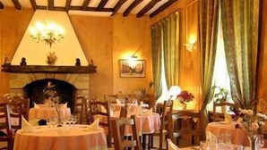 A restaurant with round tables, wooden chairs, a chandelier, and a fireplace. - Relais de la Poste (Pithiviers)