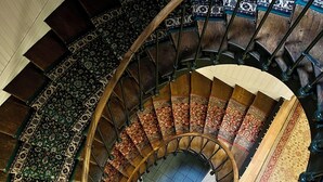 A spiral staircase with ornate carpeted steps and a wooden handrail. - Relais de la Poste (Pithiviers)