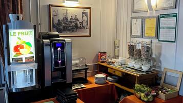 Un café con mesas, una máquina de café y un dispensador de fruta.