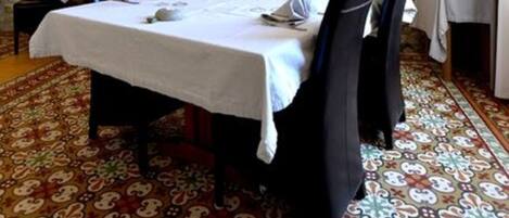 A dining room with a stone wall, a table set for six, and a patterned carpet.