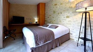 Een slaapkamer met een bed, een bureau, een stoel en een lamp.