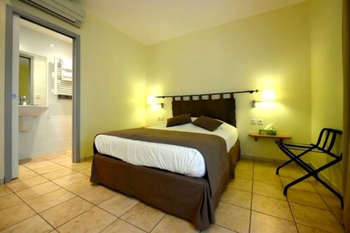 Une chambre d’hôtel avec un lit, des lampes de chevet, une chaise et une petite table.