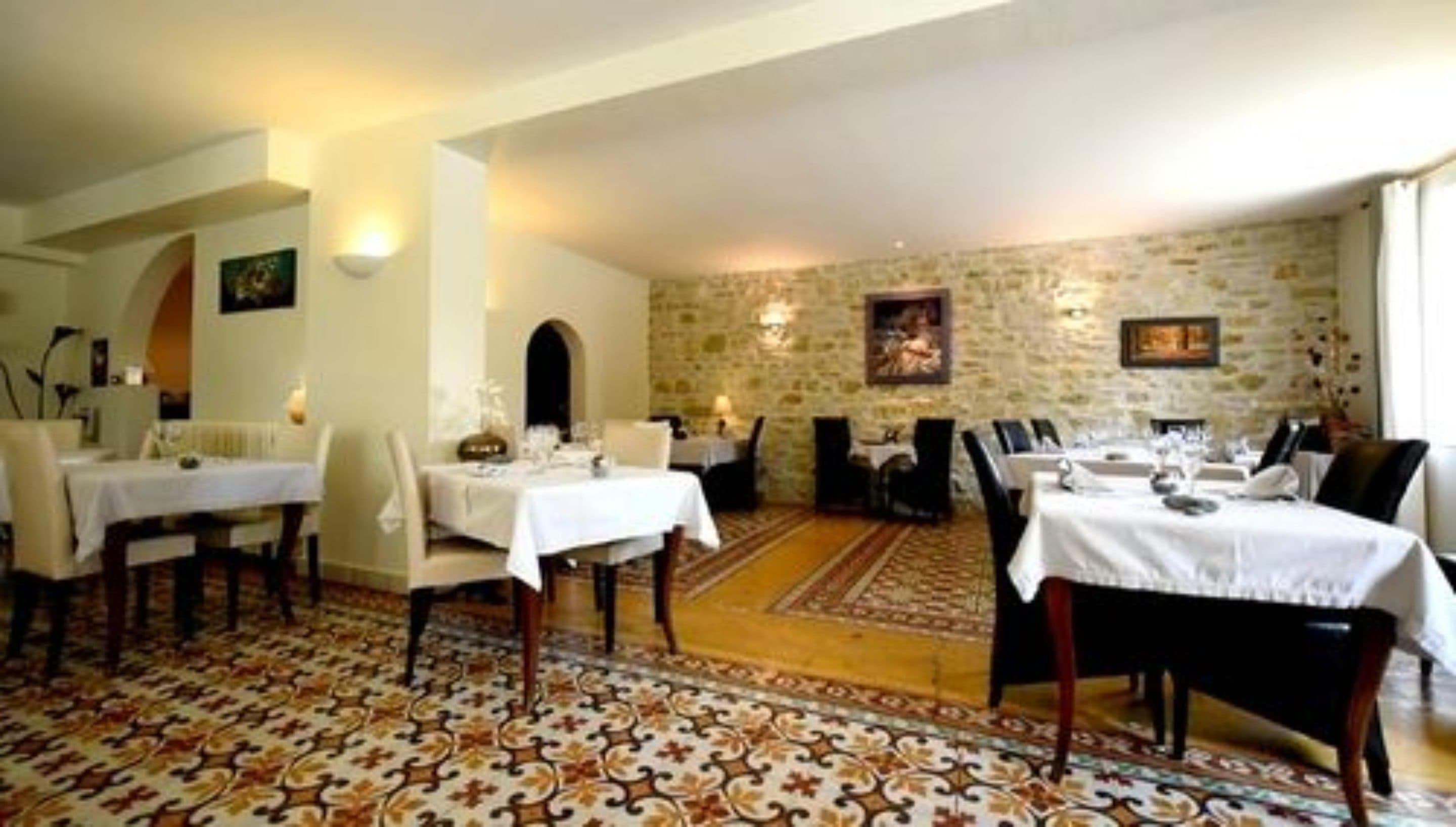 A dining area with tables set for service, stone walls, and a patterned carpet.