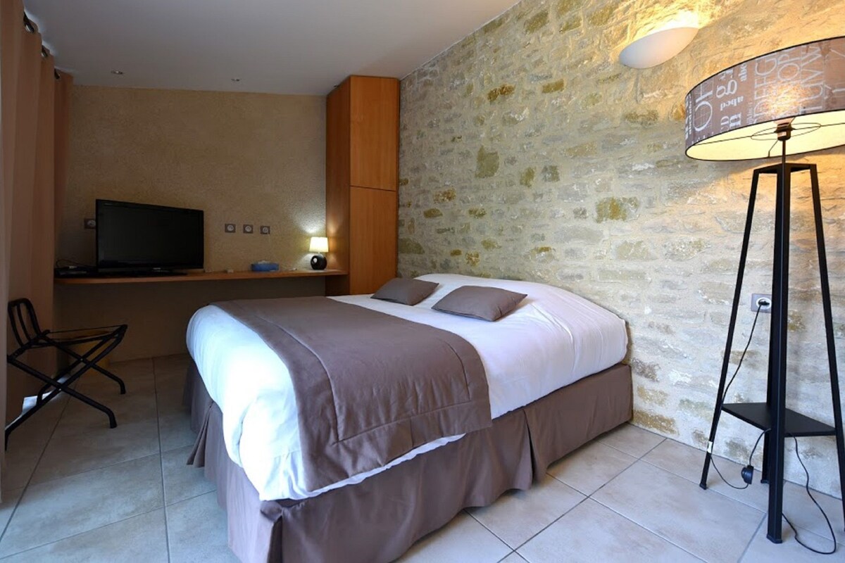 Une chambre à coucher avec un lit, un bureau avec une télévision, une lampe et une chaise.