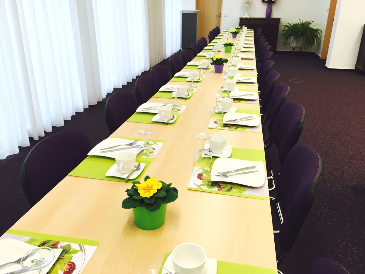 Un salón de conferencias con una larga mesa dispuesta para una reunión.