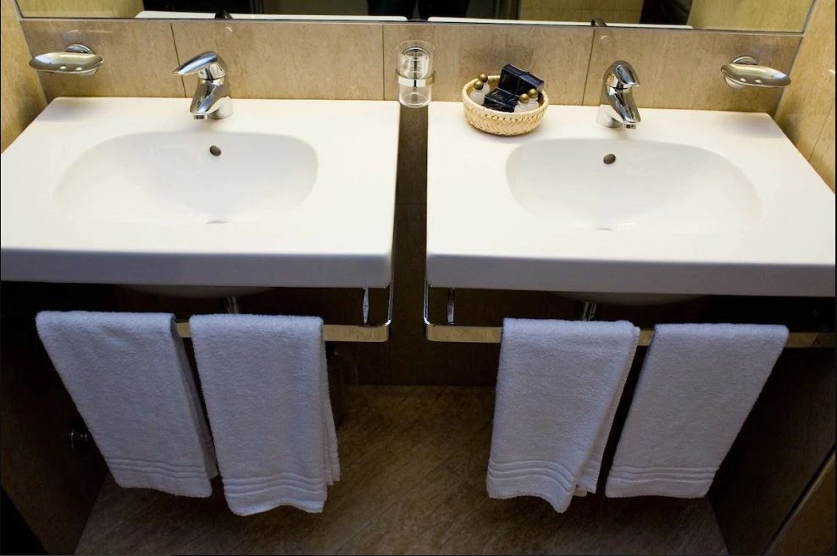 Ein Badezimmer mit zwei Waschbecken, jeweils mit einem Spiegel darüber und einem Handtuchhalter darunter.